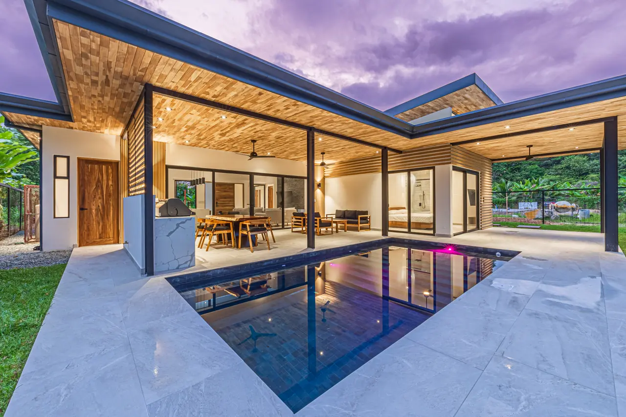 The First Build at dusk — pool lit, living space open to the deck